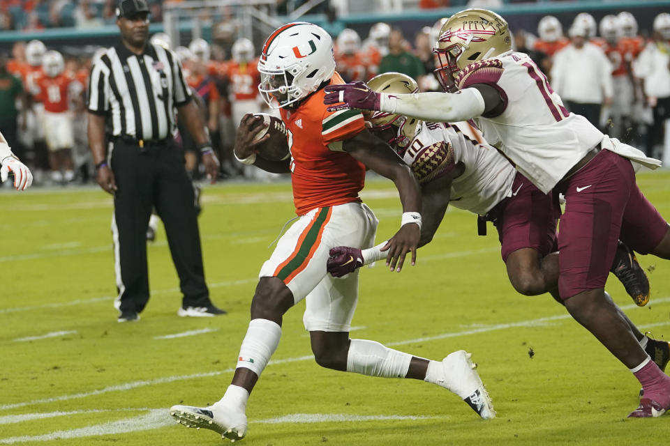 Miami quarterback Jacurri Brown, left is tackled by Florida State defensive back Jammie Robinson, center, and linebacker Tatum Bethune, right, during the first half of an NCAA college football game, Saturday, Nov. 5, 2022, in Miami Gardens, Fla.(AP Photo/Lynne Sladky)