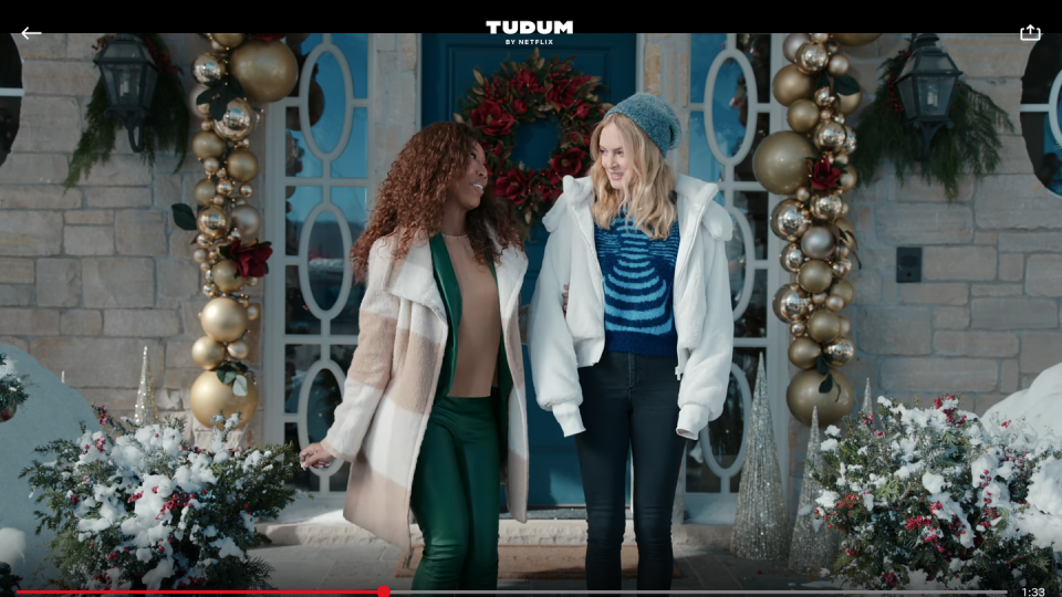 two women in front of house decorated for christmas