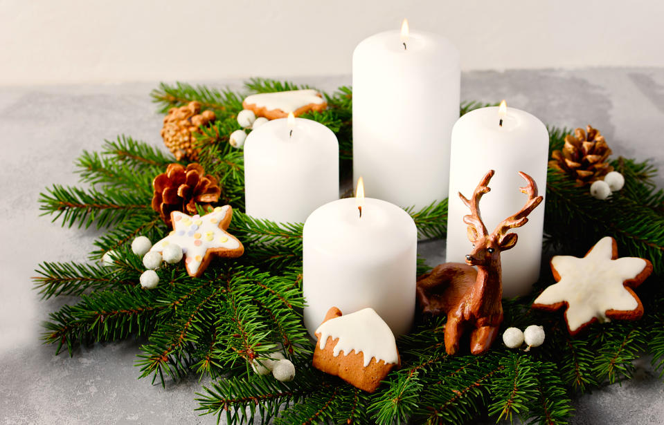 Wreaths decorating party: Four burning white advent candles in advent wreath decoration on light background. tradition in time before Christmas. Xmas lights with Christmas fir deco background concept. Festive still life.