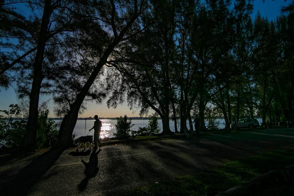 A man walks his dog along Jaycee Park in Cape Coral  early Wednesday morning, December 29, 2021. 