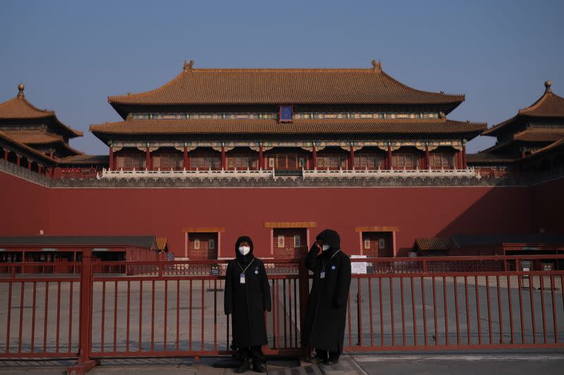 Security personnel wearing protective masks stand at the main entrance of the Forbidden City where a notice is seen saying that the place is closed to visitors for the safety concern following the outbreak of a new coronavirus, in Beijing