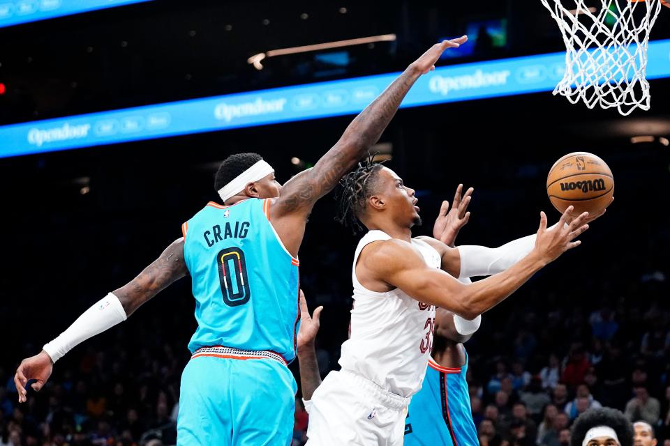 Cleveland Cavaliers' Isaac Okoro, center, drives to the basket between Phoenix Suns' Torrey Craig (0) and Deandre Alton, right, during the first half of an NBA basketball game in Phoenix, Sunday, Jan. 8, 2023. (AP Photo/Darryl Webb)