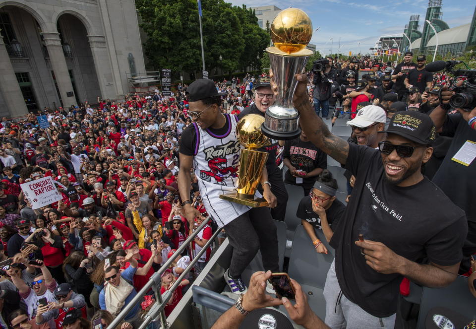 Toronto Raptors' Kawhi Leonard and Kyle Lowry hold up the trophies as they celebrate during the team's NBA basketball championship parade in Toronto, Monday, June 17, 2019. (Frank Gunn/The Canadian Press via AP)