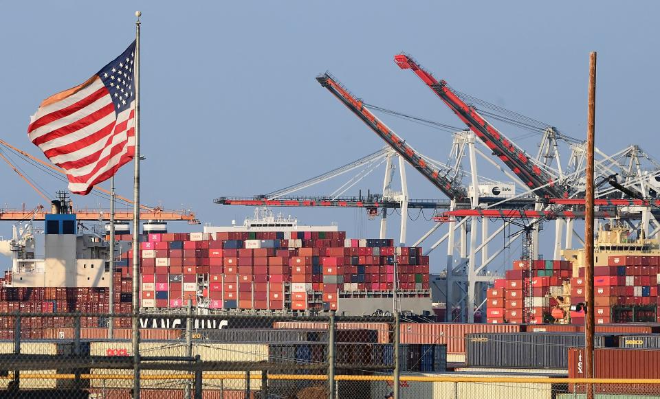 A US flag flies near containers stacked high on a cargo ship at the Port of Los  Angeles on September 28, 2021 in Los Angeles, California. - A record number of cargo ships are stuck floating and waiting off the southern California coast amid a supply chain crisis which could mean fewer gifts and toys for Christmas this year as a combination of growing volumes of cargo, Covid-19 related saftey measures and a labor shortage slow the handling and processing of cargo from each ship. (Photo by Frederic J. BROWN / AFP) (Photo by FREDERIC J. BROWN/AFP via Getty Images)