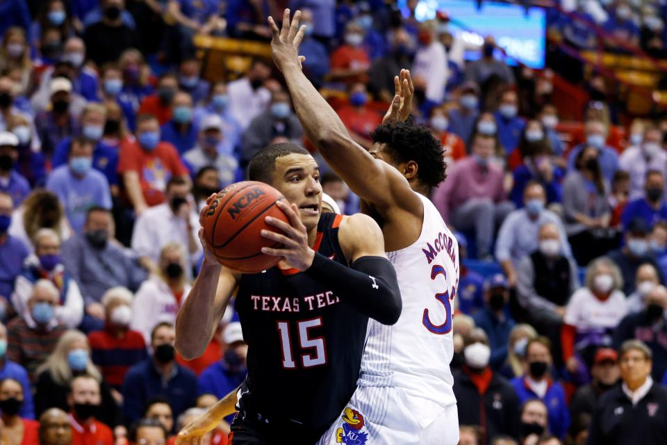 Texas Tech's Kevin McCullar (15) attempts to pass the ball against Kansas' David McCormack (33) during a Big 12 Conference game Tuesday inside Allen Fieldhouse in Lawrence, Kansas.