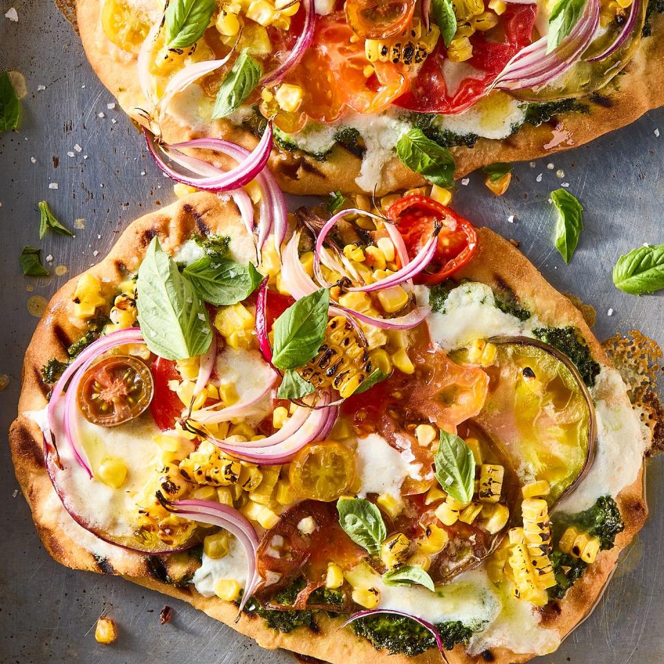 flatbread topped with pesto, corn, sliced onions, cheese, and tomatoes