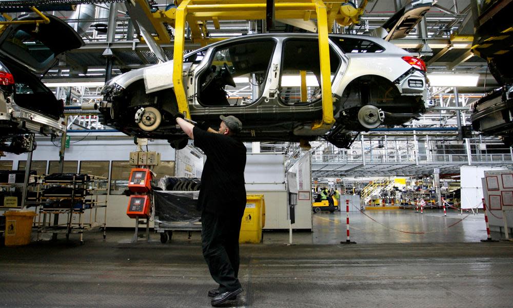 An employee works under a Vauxhall Astra car on the production line at Ellesmere Port