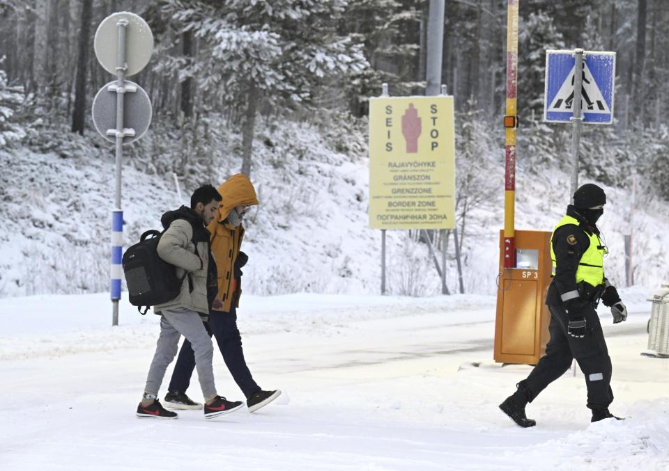 Finnish Border Guards escort migrants at the international border crossing between Finland and Russia, in Salla, Finland, Thursday, Nov. 23, 2023. (Jussi Nukari/Lehtikuva via AP)