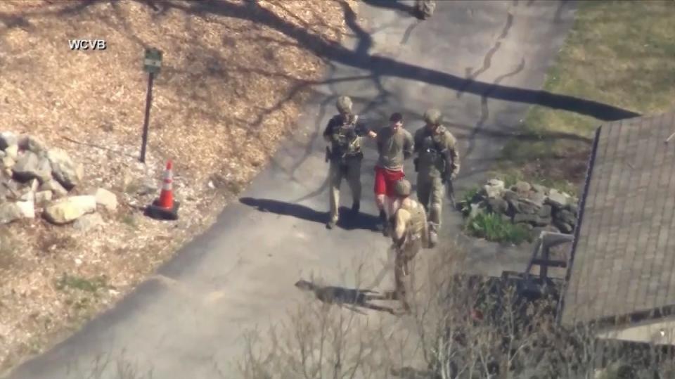 Esta imagen tomada de un video proporcionado por WCVB-TV muestra a Jack Teixeira, en camiseta y pantalones cortos, siendo detenido por agentes tácticos armados el jueves 13 de abril de 2023 en Dighton, Massachusetts. (AP)