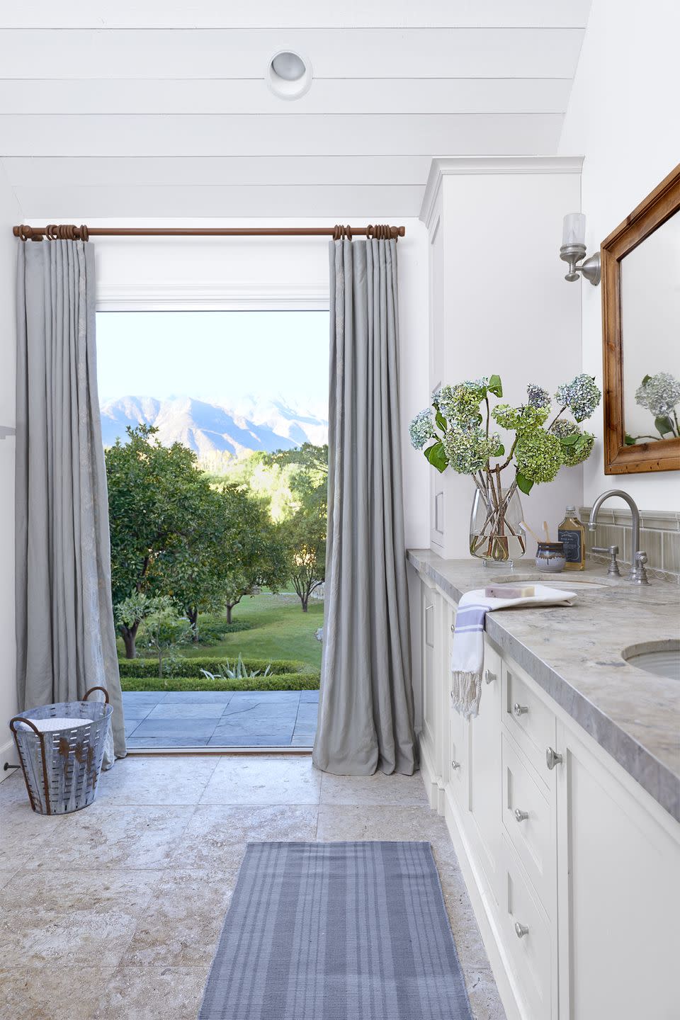 bathroom with limestone tile floor and an open door looking out to the california mountains