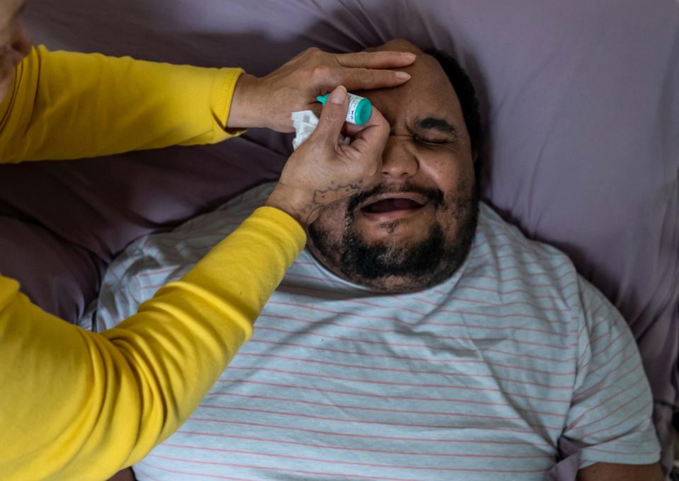 Marvin McQueen Jr. winces as his mother, Debra Westbrook, administers eyedrops for his glaucoma on Thursday, Feb. 10, 2022. 