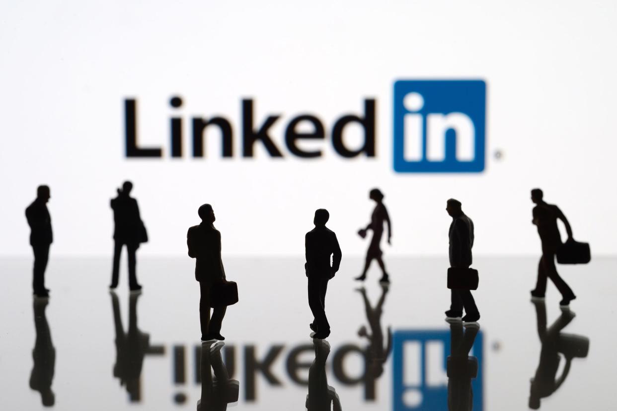 human figurines standing in front of Apple iPad monitor displaying LinkedIn logo