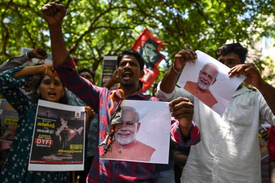 Protesters shout slogans and burn placards with pictures of Prime Minister Modi (AFP via Getty)