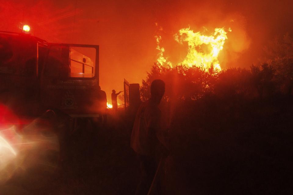 Firefighters try to extinguish the flames in a forest in Avantas village, near Alexandroupolis town, in the northeastern Evros region, Greece, Monday, Aug. 21, 2023. Gale-force winds are fanning the flames of wildfires across Greece, including 53 new blazes that broke out early Monday amid hot, dry and windy weather that has sucked moisture from vegetation. (AP Photo/Achilleas Chiras)