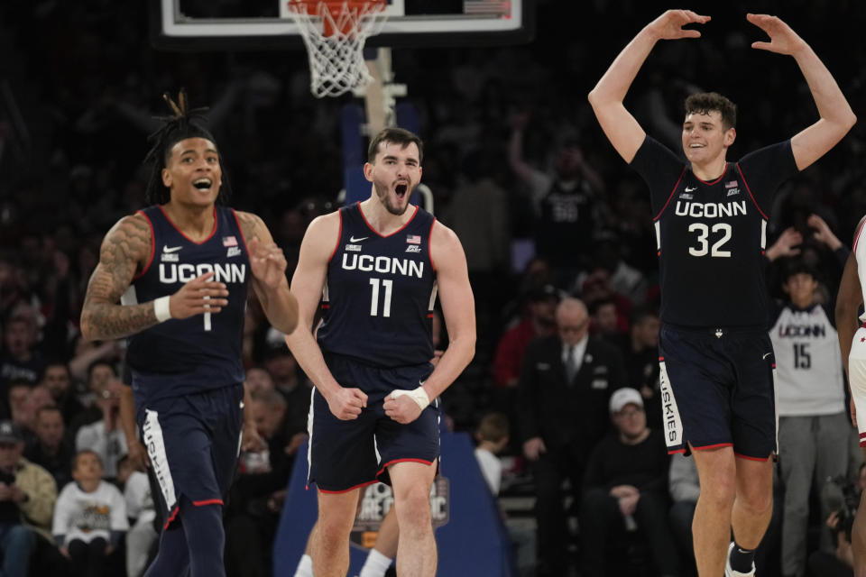 UConn's Solomon Ball (1), left, Alex Karaban, center, and Donovan Clingan (32) react during the second half of an NCAA college basketball game against Indiana, Sunday, Nov. 19, 2023, in New York. (AP Photo/Seth Wenig)