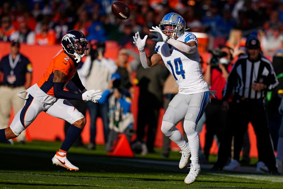 Detroit Lions wide receiver Amon-Ra St. Brown (14) catches a pass against Denver Broncos cornerback Pat Surtain II (2) during the first half of an NFL football game, Sunday, Dec. 12, 2021, in Denver.
