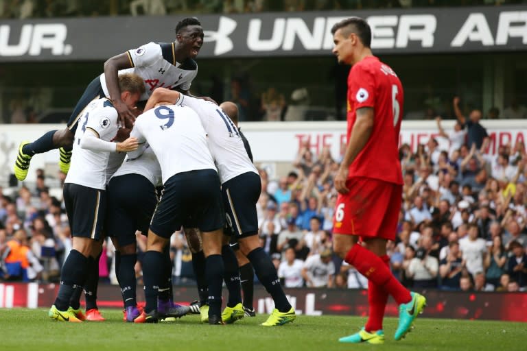 Tottenham Hotspur's Victor Wanyama jumps onto teammates as they celebrate a goal by English defender Danny Rose during a English Premier League football match against Liverpool at White Hart Lane in London, on August 27, 2016, which was a 1-1 draw