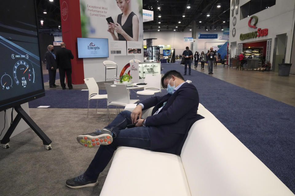 An attendee rests on a couch during the CES tech show Thursday, Jan. 6, 2022, in Las Vegas. (AP Photo/Joe Buglewicz)