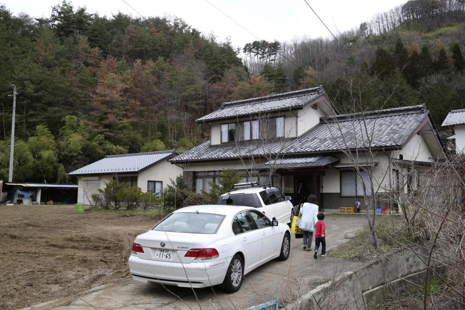 In this Saturday, April 5, 2014 photo, a boy arrives with a woman at a dormitory where Kokoro Kamiyama, a 13-year-old girl who fled Fukushima is starting here new life, in Matsumoto, central Japan. Kamiyama is the first child to sign on to the Matsumoto project which Chernobyl-doctor-turned-mayor Akira Sugenoya of Matsumoto, offered his Japanese town to get children out of Fukushima. Kamiyama was prone to skipping school when she was in Fukushima, which her mother believes was a sign of stress from worrying about radiation. Now she is happy she can run around outdoors in the city without wearing a mask. (AP Photo/Koji Sasahara)