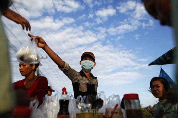 Un hombre vende comida a los trabajadores textiles a la entrada de la fábrica. (Reuters/Damir Sagolj).