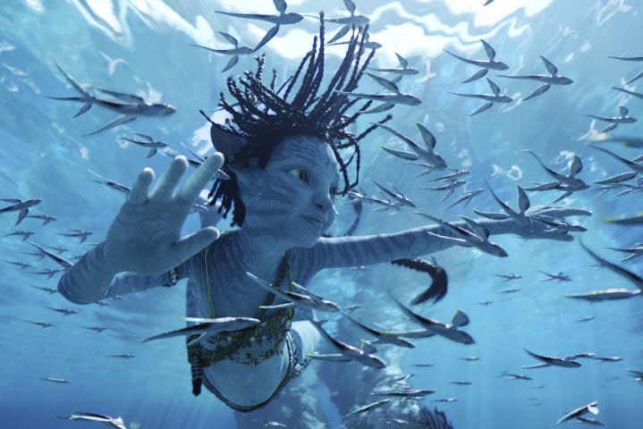 A blue-skinned Na'vi child swims underwater in a scene from Avatar: The Way of Water.