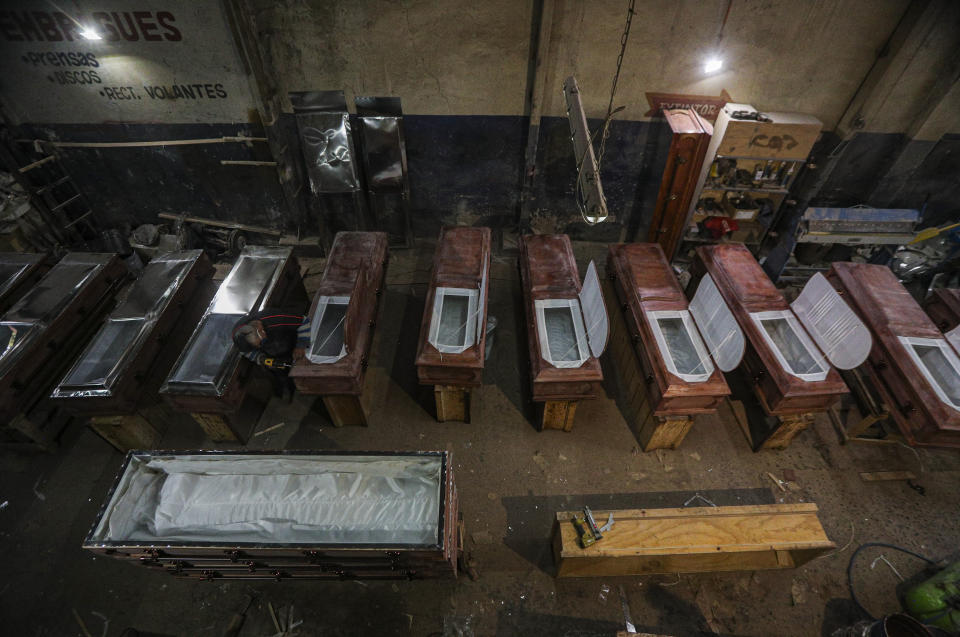 El migrante peruano dedicado a hacer ataúdes César Ambrosio, termina los detalles de una línea de producción en la funeraria Bergut en Santiago, Chile, el jueves 18 de junio de 2020. (AP Foto/Esteban Felix)