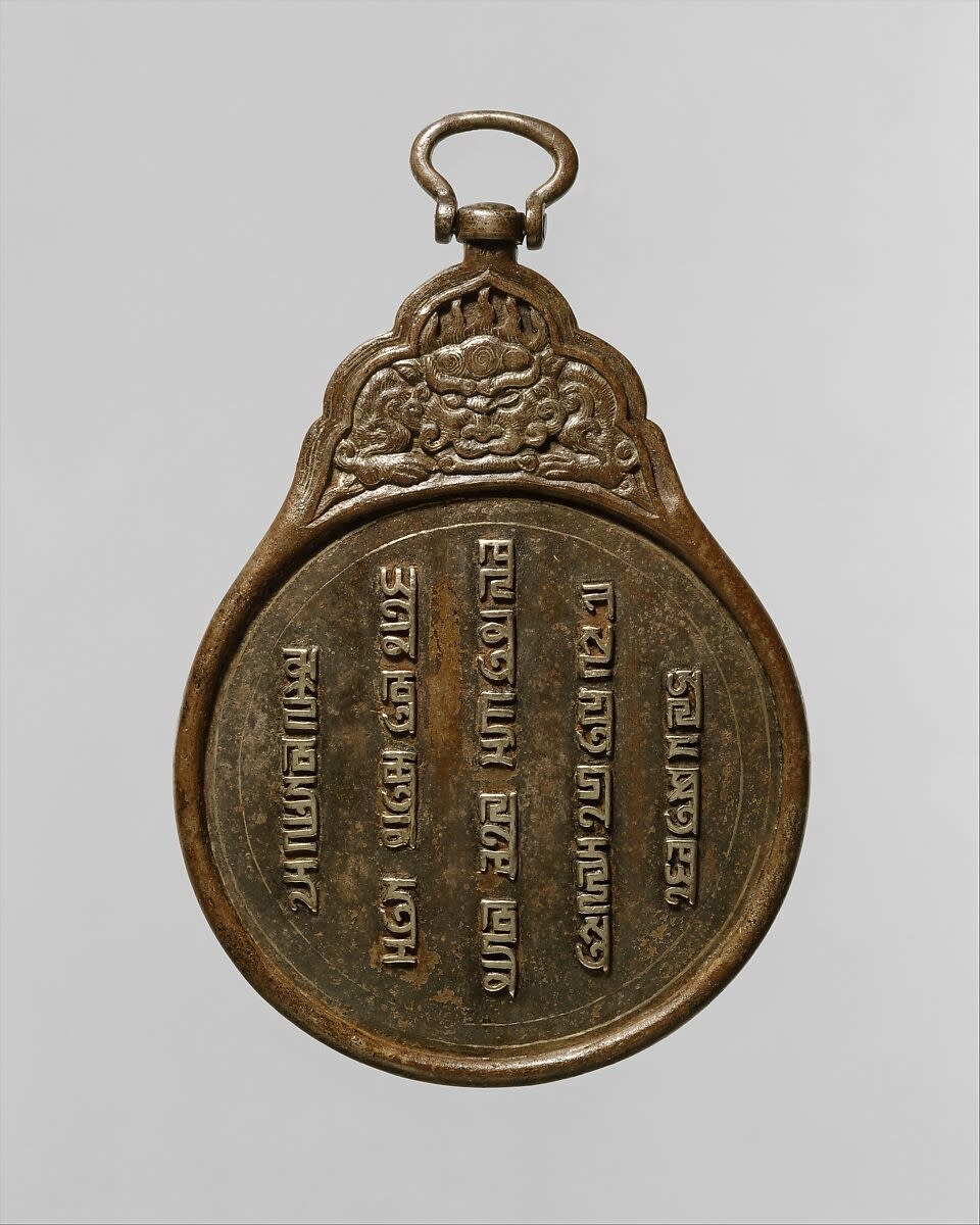 A spherical, metallic hanging badge with inscription