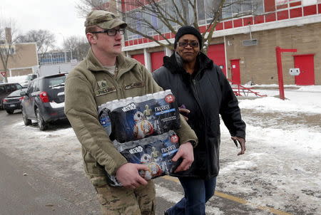 Michigan National Guard Staff Sergeant William Phillips (L) assists a Flint resident with bottled water at a fire station in Flint, Michigan January 13, 2016. REUTERS/Rebecca Cook