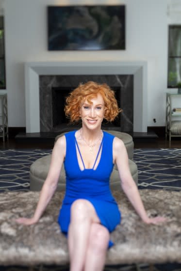 A woman with short red hair sitting in a blue dress