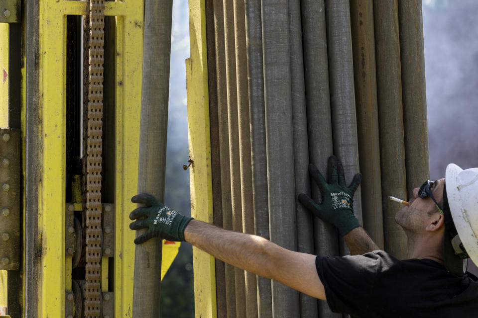 A Dandelion Energy employee inserts a drill extension while putting in a geothermal heat pump system at a home in White Plains, N.Y., Monday, May 8, 2023. A water-filled loop of flexible piping is run several hundred feet deep, and either carries heat away from, or into the house, depending on the season. Industry experts see the technology becoming increasingly popular in the coming years. (AP Photo/Julia Nikhinson)