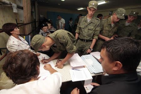 Russian servicemen receive ballot papers at a polling station before voting in the Crimean port of Sevastopol, September 14, 2014. REUTERS/Stringer