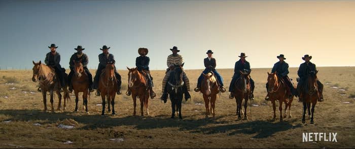 9 gunslingers sitting on their horses look into the camera.