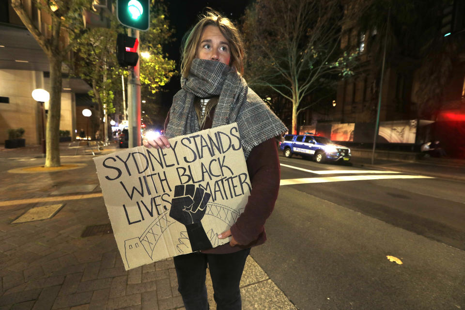 A protester from St. Louis, U.S., who gave her name as Merinda, carries a handmade sign as demonstrators gather in Sydney, Tuesday, June 2, 2020, to support the cause of U.S. protests over the death of George Floyd and urged their own governments to address racism and police violence. Floyd died last week after he was pinned to the pavement by a white police officer who put his knee on the handcuffed black man's neck until he stopped breathing. (AP Photo/Rick Rycroft)