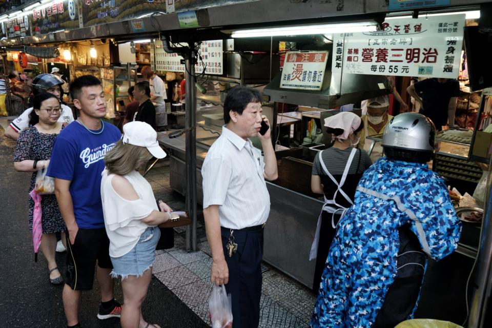 遊客在廟口夜市的營養三明治攤子前排隊購買。   圖：張良一/攝