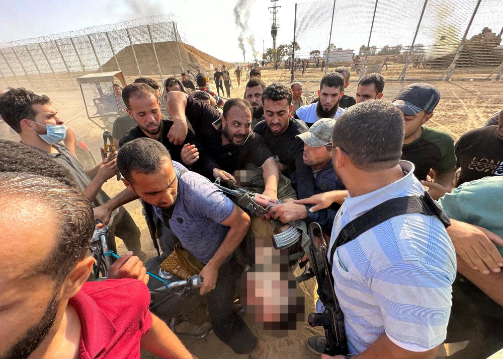 Gunmen carry the body of a dead Israeli in southern Israel on 7 October. Photograph: Mohammed Fayq Abu Mostafa/Reuters 