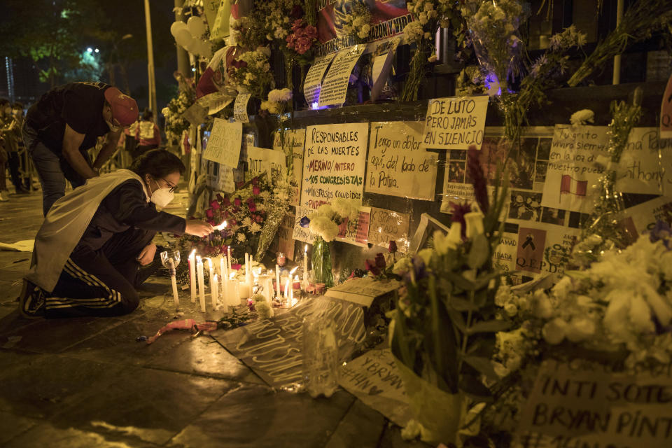 A woman lights a candle in a memorial for the victims of the recent protests, outside the Congress building, as they wait for news from inside on who will be the country's next president, in Lima, Peru, Sunday, Nov. 15, 2020. Interim President Manuel Merino announced his resignation following massive protests unleashed when lawmakers ousted President Martin Vizcarra. (AP Photo/Rodrigo Abd)