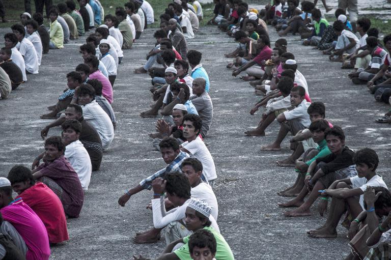 New arrivals sit in lines at a newly set up confinement area in Bayeun on May 21, 2015, after more than 400 migrants from Myanmar and Bangladesh were rescued by Indonesian fishermen off the coast of Aceh province a day earlier