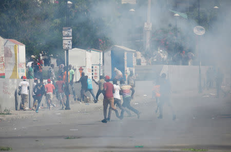 Protesters run amid tear gas during a march to demand an investigation into what they say is the alleged misuse of Venezuela-sponsored PetroCaribe funds, in Port-au-Prince, Haiti, October 17, 2018. REUTERS/Andres Martinez Casares