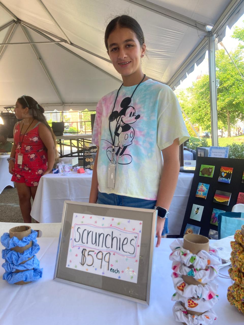 Samara Kazan, 14, stands at her table at the Dream Makers Market in Wing's Court, downtown New Bedford, Thursday, July 14. Kazan's offerings included an assortment of her handmade hair scrunchies.