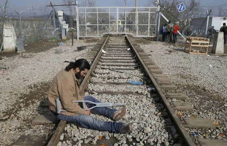 A migrant sits on a disused railway track next to the Greek-Macedonian border fence, at a camp near the Greek village of Idomenii March 1, 2016. REUTERS/Marko Djurica