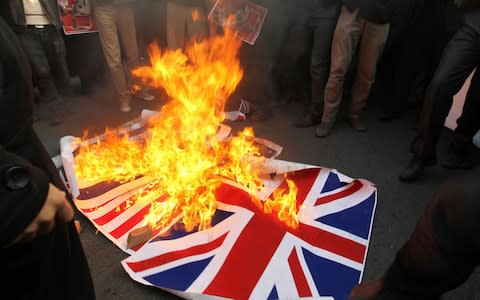 Iranian protesters burn mock-ups of the British flag outside the embassy in Tehran on November 29, 2011. - Credit: ATTA KENARE/AFP