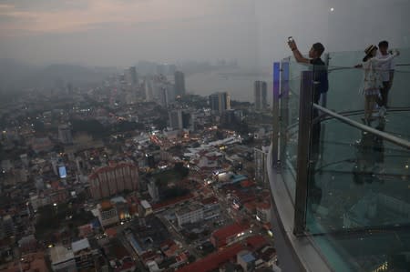 Tourists take pictures of the skyline at The Top Komtar, in Penang