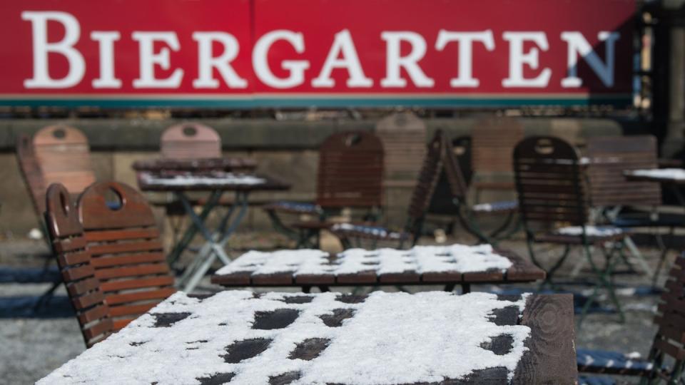 Noch sind die Tische und Stühle in einem Biergarten mit Schnee bedeckt. Foto: Sebastian Kahnert