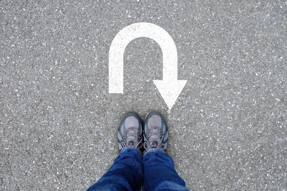 A person standing with a u turn sign on the ground in from of them.