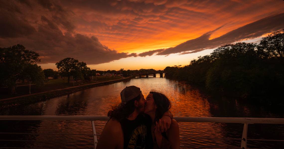 A couple share a kiss underneath a sky of Mammatus clouds near the Keeper of the Plains on Tuesday. Travis Heying/The Wichita Eagle