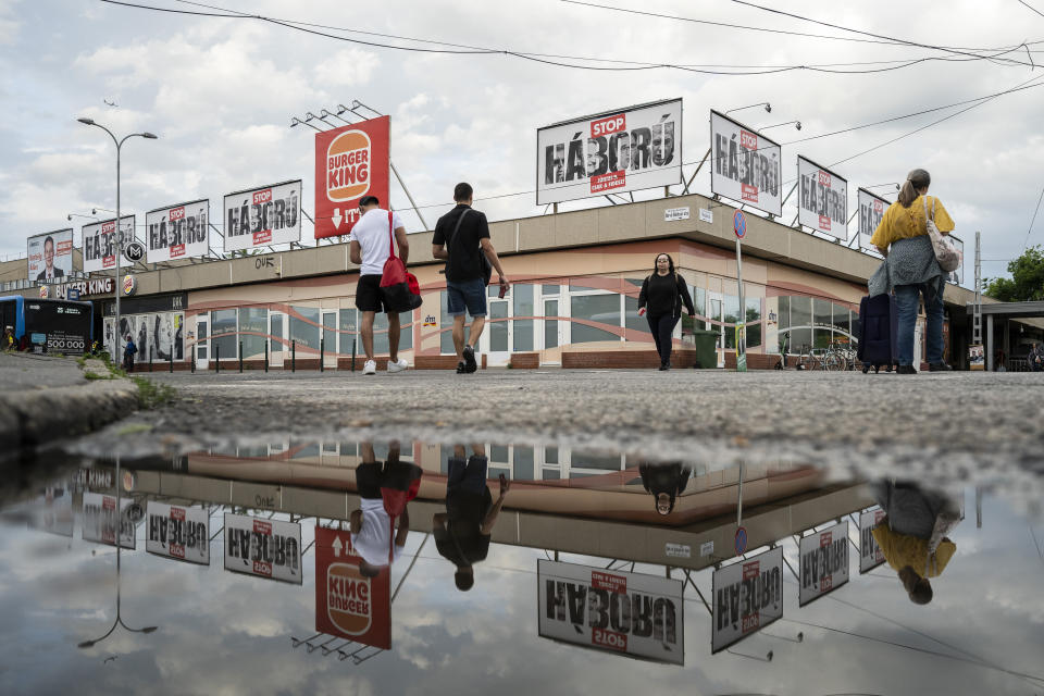 People walk next to billboards with a message declaring "Stop War" have been erected on the streets of Budapest, Hungary, on May 21, 2024. A campaign message is unavoidable as thousands of billboards have been erected, featuring the faces of Péter Magyar, Budapest's liberal mayor, a former socialist prime minister and George Soros. (AP Photo/Denes Erdos)