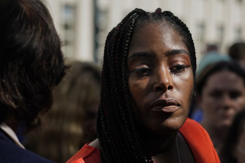 A woman with braids looks off camera