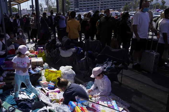 Families mostly from Russia camp out near the San Ysidro Port of Entry into the United States, as a stream of pedestrian border crossers file past them, in Tijuana, Mexico, Thursday, March 17, 2022. About three dozen would-be asylum seekers from Russia found themselves blocked from entering the U.S. on Friday while a group of Ukrainians flashed passports and were escorted across the border. (AP Photo/Gregory Bull)