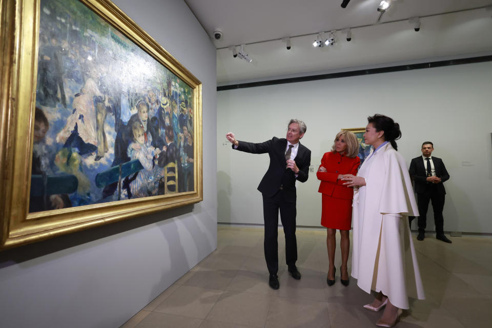 China's President Xi Jinping's wife Peng Liyuan, right, and French President Emmanuel Macron's wife Brigitte Macron, center, watch Bal du moulin de la Galette by Auguste Renoir as they visit the Orsay Museum, Monday, May 6, 2024 in Paris. China's President Xi Jinping is in France for a two-day state visit that is expected to focus both on trade disputes and diplomatic efforts to convince Beijing to use its influence to move Russia toward ending the war in Ukraine. (AP Photo/Aurelien Morissard, Pool)