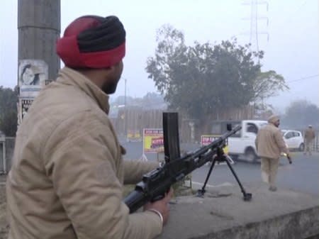 A policeman stands guard with a gun as vehicles pass by, following an attack on an Indian Air Force base in Pathankot on Saturday, near the border with Pakistan, in Ludhiana, Punjab state, India, in this still frame taken from video, January 2, 2016. REUTERS/ANI/via Reuters